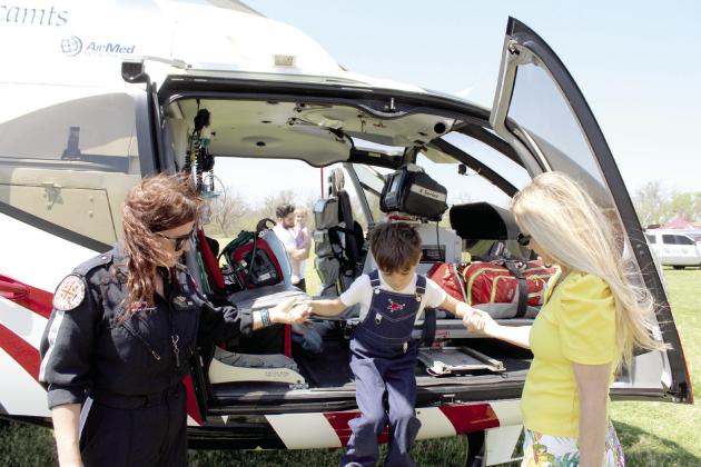 Flight Medic Brittney Little, left, and Jerica Sasse help Jett Sasse, 6, of Edmond, down from the Air EVAC Lifeteam EC130 helicopter, out of Seminole, during the Touch A Truck and Beyond event, held at the Citizen Potawatomi Nation Festival Grounds on April 12. There was also a helicopter from the Air &amp; Marine Operations US Customs &amp; Border Protection at the event.