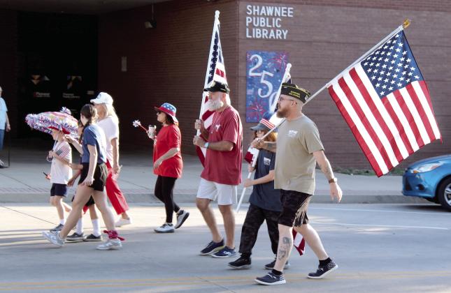 Shawnee VFW members, Past Commander Patrick Koch, Killian Keathley and Michael Keathley, carry flags in the Shawnee Independence Day Parade on July 4. Shown in the background is the Shawnee Public Library's community tile artwork celebrating the 250th USA anniversary. The parade started at the Pottawatomie County Museum at 7:30 am and ended at Woodland Veterans Park with a presentation. Photos by Natasha Dunagan, Countywide &amp; Sun