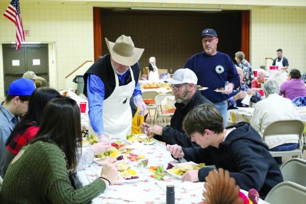 Tecumseh Police Chief J.R. Kidney and Ron Holman serve pie to a family at the 19th Annual Tecumseh Family Thanksgiving Dinner, held at Tecumseh City Hall Auditorium on Nov. 28. Started by Randy and Suzanne Gilbert, the event fed about 500 people in the auditorium and 680 to-go orders for a total of 1,180 this year, said S. Gilbert. They had around 20 volunteers, and all left-over food went to the Shawnee Rescue Mission. Countywide &amp; Sun/Natasha Dunagan