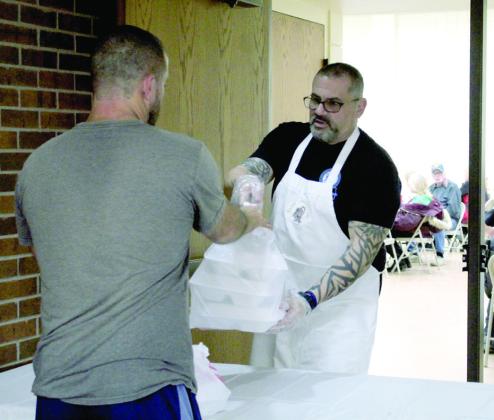 Retired OKC Police Officer John Blumenthal hands out to-go meals at the 19th Annual Tecumseh Family Thanksgiving Dinner, held at Tecumseh City Hall Auditorium on Nov. 28. Blumenthal volunteered with his mother, Louise Blumenthal, and son, Mason Blumenthal, this year. Countywide &amp; Sun/Natasha Dunagan