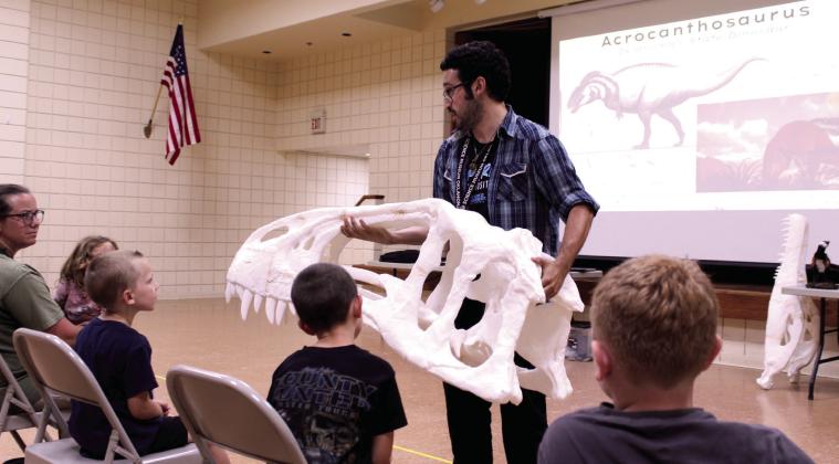 Science Museum Oklahoma Educator Calen Cavallaro holds half of a 3D-printed skull belonging to the Acrocanthosaurus, Oklahoma's State Dinosaur, at the "Dino or Not? The Ultimate Prehistoric Showdown" program at Tecumseh Public Library on July 16. In addition to looking at replica and real fossils, kids could choose paper body parts and create their own dinosaurs. Photos by Natasha Dunagan, Countywide &amp; Sun