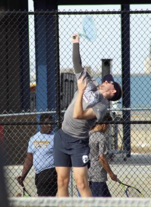 Shawnee senior Carter Schollenbarger reaches high to serve during the Tennis Scrimmage against Tecumseh.