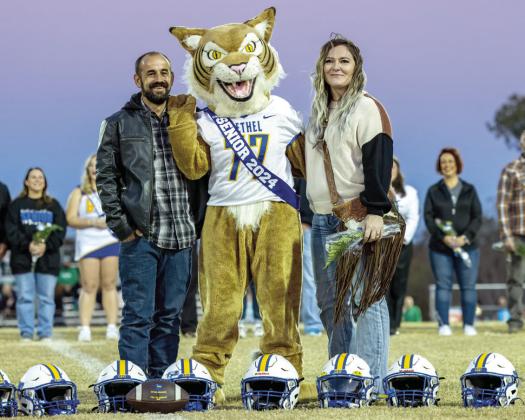 Cloe Gitchell, the Bethel Wildcat mascot, poses with her parents during Bethel’s Senior Night ceremonies.
