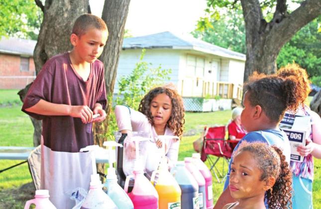 Kash Tillis, 9, and Makayla Tillis, 10, serve snowcones to children during "The Block is Hot: Live Music Block Party" on May 28 in the Dunbar Heights neighborhood of Shawnee. They are the grandchildren of Remetia Tillis who owns "Two Chicks Cookin'" food truck.