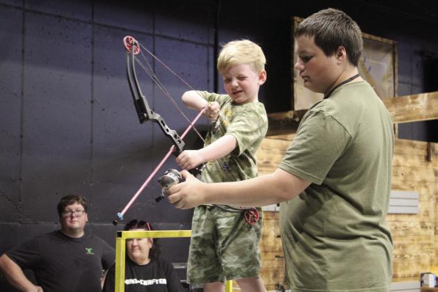 Damian Pearson, 5, of Marlow, is assisted in target bowfishing by Zak McMunn, of Darkwater Adventures in Meeker, during the Outdoor Nation Expo on Aug. 11, 2023 at FireLake Arena. File photo