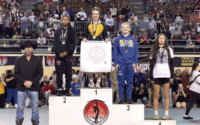 Tecumseh senior Vivian Hayes placed first in her weight division of the OSSAA Class 5A Girls Wrestling State Championship on March 1 at the State Fair Arena. Hayes is the first THS student athlete to win state in girls wrestling, and Head Wrestling Coach Billy Don Sigman stands by, far left. Bethel senior Dixie Holliday was also in the 105 weight class and placed third. Photo provided