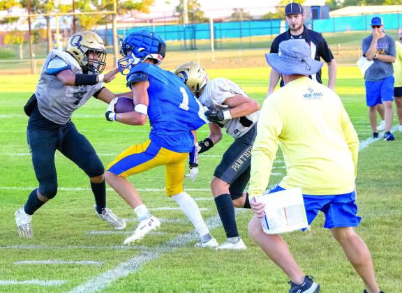 Bethel’s Reagan Curry tries to run the ball around two Okemah players during a scrimmage on Aug. 25, as the referree blows his whistle. Bethel also played Woodland that day. Photo provided by Richelle Treece.