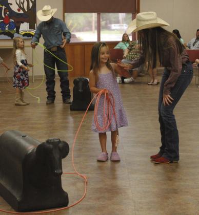 Paula Wiley, 5, of McLoud, gets a high-five from Jasey Graves after learning how to throw a lasso. Also shown is Tatum Roberts, who is helping Isabel Nunes, 6, of Shawnee. Shawnee Public Library Branch Manager Mary Sims said this is the 15th year for six IFYR youth directors to visit the library. Sims also interviewed them about their rodeo experiences, and a 'chuckwagon snack' was provided by Lindsey Cowan, Jennifer Gates and Chloe Gates of the Junior Service League.