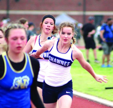In a relay race, Shawnee runner Maryl Lewellen passes the baton to Maranda Bieber.
