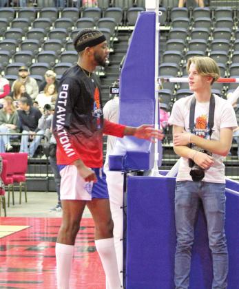 Landon Kidney, right, talks with former Potawatomi Fire player Calvin Giles during their first home game on March 19. At only 15, Kidney has served as the team's photographer in their first season.