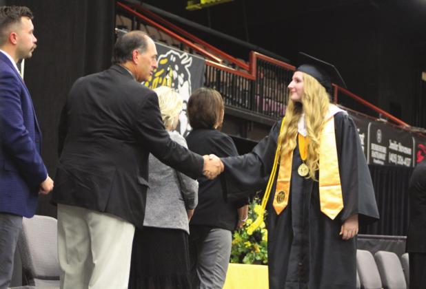 Tecumseh Co-Valedictorian Elizabeth Kipps shakes hands with TPS Board Member Todd Kennedy before receiving her diploma on May 18. Tecumseh High School graduated 144 seniors that evening.