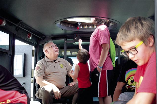 Lt. Keith Williams of the Oklahoma Highway Patrol smiles as two young people look out the hatch of an armored vehicle during Cops n’ Kids at the Heart of Oklahoma Expo Center on Aug. 27. Countywide &amp;amp; Sun/Natasha Dunagan
