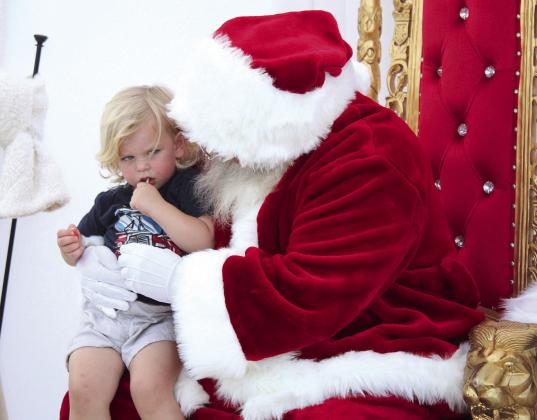 Elliot Lowry, 2, of Tecumseh, looks suspiciously at Santa during Cops n’ Kids. Santa was sponsored by A/C Doctors Heating and Air to pose for Christmas cards.