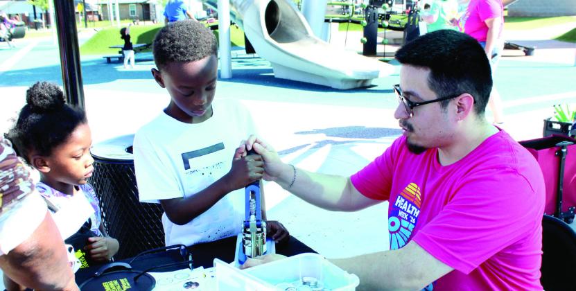 Shawnee Public Library Children's Librarian Jairo Montelongo helps Nicolaus Miller, 7, to use the button maker, as Nikailyn Miller, 5, both of Shawnee, waits her turn. Pioneer Library System's Summer Learning Challenge is happening now through Aug. 15, and they have a goal of 20 million points this year. Natasha Dunagan, Countywide &amp;amp; Sun