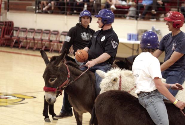 Earlsboro Police Chief Christopher Bayless, with the Hoof Patrol team, looks to pass during the Third Annual Earlsboro Donkey Basketball fundraiser on April 4 at the EHS Gym. Shown, from left, are Anthony Glasgow, Bayless, Bayless's son, Easton Barnes, and firefighter Caleb Inman. See full cutline below.