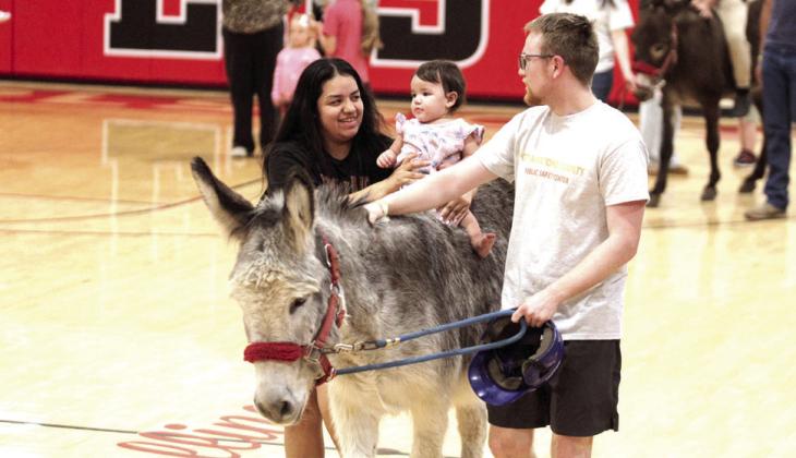 Toricelyn Harjo holds onto one-year-old Elianna Harjo for a donkey ride. John Cole, with the Pottawatomie County Public Safety Center, leads the donkey.