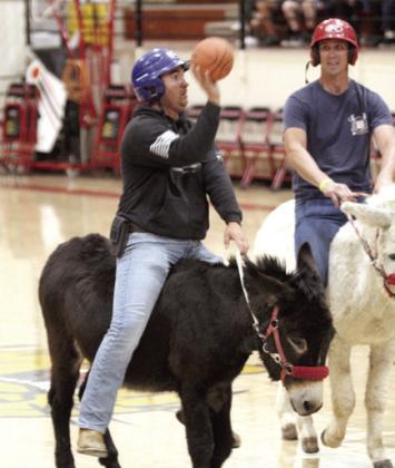 Officer Anthony Glasgow, with the Hoof Patrol, tries for a bucket. Also shown is firefighter Caleb Inman.