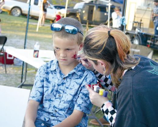 Asher eighth-grader Alice Middleton paints on the face of Everest Headley, 7, of McLoud, during the Second Annual Macomb 21st CCLC Trade Days on Sept. 28. Countywide &amp; Sun/Natasha Dunagan