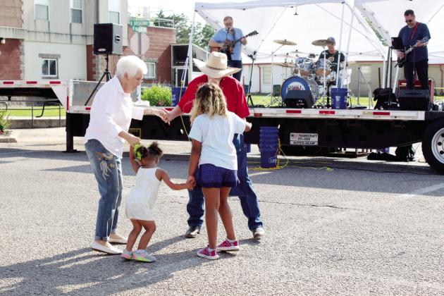 As the band House Special plays, Genesis Robbins, 2, and Zoe Robbins, 8, both of Tecumseh, dance with Rita Yarbrough of Shawnee and Jerry Yarbrough of Sparks during the Mingle on Main Street Block Party on June 8. The Yarbroughs invited the girls to dance with them at the corner of Broadway and Washington in Tecumseh. Countywide &amp; Sun/Natasha Dunagan