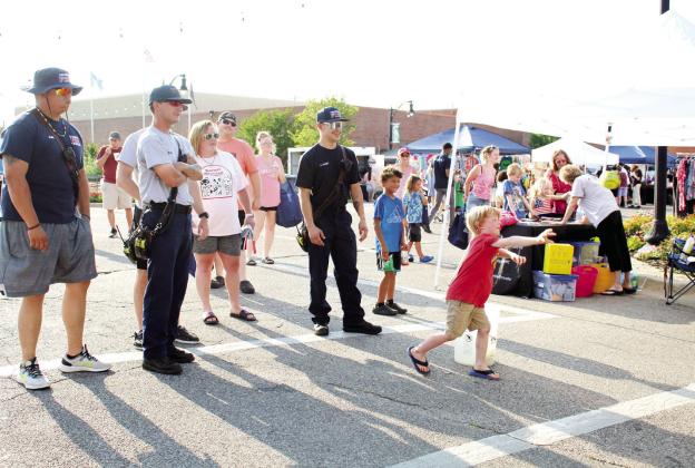 Joseph Tucker, 5, of Tecumseh, gives his best throw at the Hearing Health Care Inc. dunking booth, as three Tecumseh firefighters lend support during the Mingle on Main Street Block Party, June 8. Countywide &amp; Sun/Natasha Dunagan