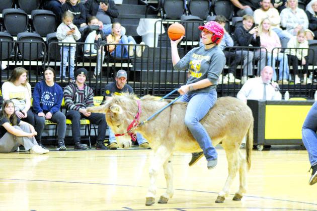 Tecumseh High School Science Teacher Natalie Belshe moseys toward the basket, as Superintendent Robert Kinsey emcees the game.