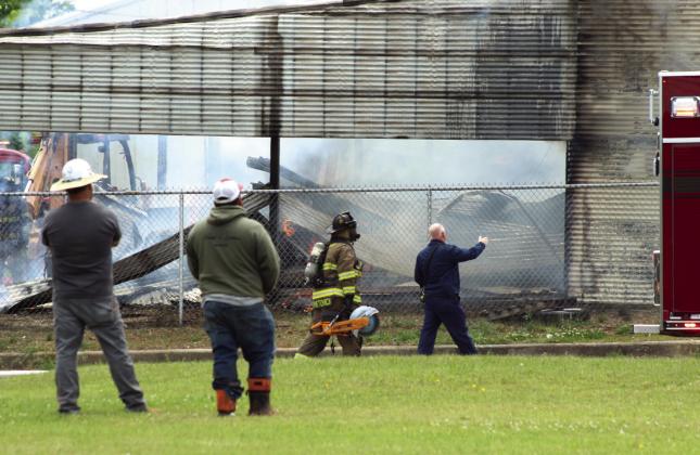 Tecumseh Fire Chief Rhett Banks, far right, directs firefighter Conner Franetovich, who was using a gas-powered circular saw to gain access to the fire in the Jordan Contractors, LLC mechanic shop in downtown Tecumseh on May 6. Natasha Dunagan, Countywide &amp; Sun
