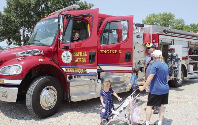 Noah, 6, and Mila, 5, enjoy learning about a Bethel Acres Fire Rescue engine, as Patience, 3, heads back to her stroller, and mother Donna Bennett, all of Tecumseh, and firefighter Orrin Beckham watch during the Touch A Truck portion of the FireLake Fireflight Balloon Festival on Aug. 8. Shawnee Fire Department, Brown and Sons Towing and Recovery, and others also brought their vehicles.