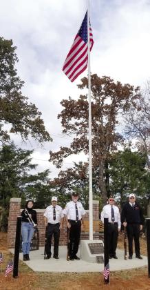 A bugler from OBU and the VFW Post 1317 Honor Guard pose at the Brown Cemetery Veterans Memorial during a dedication ceremony on Nov. 11. The memorial includes a wall, 32-foot flag pole with the five military brances plaque, bench and “Freedom Isn’t Free” metal sign. It was spearheaded by Karen Hilditch and her brother Bobby Cearley who are now planning to place 122 wreaths on veterans graves at the cemetery, six miles west of Tecumseh. Photo provided.
