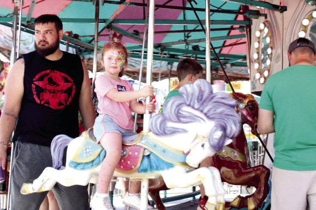 A girl rides on the carousel at the McLoud Blackberry Festival on June 21. Relocated to the southern half of the McLoud Veteran Park, all of the carnival rides and vendors had to be arranged on higher ground due to muddy conditions. In this area, Pottawatomie County workers provided and applied gravel, said Melanie Krause with the McLoud Chamber of Commerce.