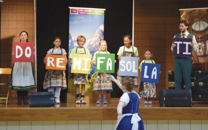 Lyric Theatre of OK's Maddie Wall (Fraulein Maria), bottom center, teaches the famous "Do-Re- Mi" song with help from cast member Kristin Kuns (Liesl), Volunteer CPN Students (the youngest five Von Trapps) and Lucas Schrantz (Friedrich).