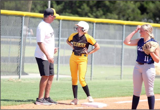 Tecumseh Head Fast-Pitch Coach Chad Trahan talks with sophomore Madison Gray after she hit a triple, as Shawnee’s Karma Mason looks on, during the Dale-Tecumseh Tournament game on Sept. 5. The Lady Wolves lost to the Lady Savages, 10-0. Tecumseh won four out of their five games, and Shawnee won two. Dale won the tourney with no losses.