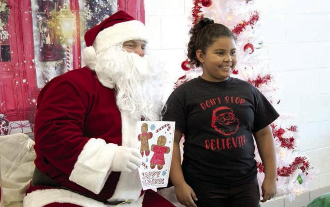 Josslyn Springer, 8, of Shawnee, poses with Santa who is holding her coloring page during the Second Annual Breakfast with Santa, held at Shawnee Middle School on Nov. 30.
