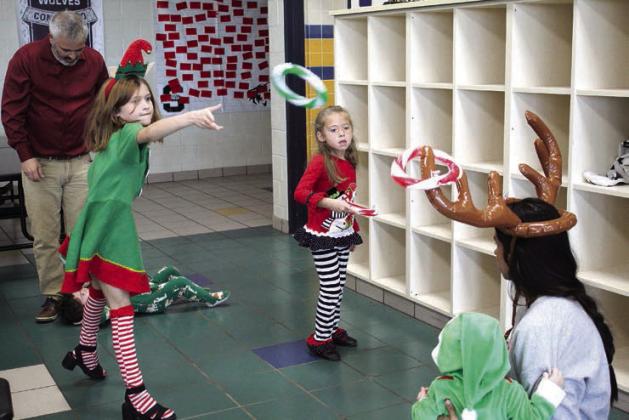 Peyton Neely, 9, and Addy Pellman, 5, play reindeer ring toss, as Serena Neely wears the antlers and hold baby Oliver Neely. Also shown are Justin Neely and Merritt Neely, 2.