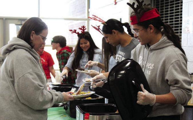 Shawnee wrestlers - including Elias Shields and Jaxon Shawnee, in foreground - serve breakfast for Jennifer Carter during the Second Annual Breakfast with Santa, held at Shawnee Middle School on Nov. 30. The event was a fund-raiser for the Shawnee Wrestling Program.