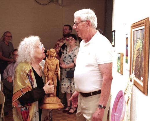 Norma Neely talks with artist John Blum after choosing his sculpture.