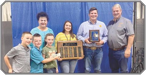 Cooper Kline receives the Ann (Sis) Gilbert award at the 2021 Pottawatomie County Free Fair. The award is presented by the Gilbert family, Randy, Annie Jo, Suzanne, Bryar, Legend and Taycie. Morley Griffith is holding the plaque with all past winners.