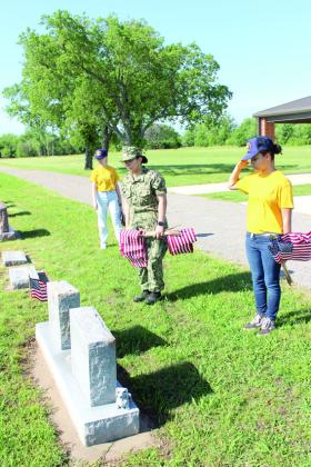 U.S. Naval Sea Cadet Recruit Ziah Jefimoff salutes after placing a flag on the grave of WWII veteran Arville M. Howard at the Tecumseh Cemetery. Also shown are fellow recruit Chloe Conkling and Seaman Apprentice Ava Rivera of the U.S. Naval Sea Cadet Patriot Division. Natasha Dunagan, Countywide &amp; Sun