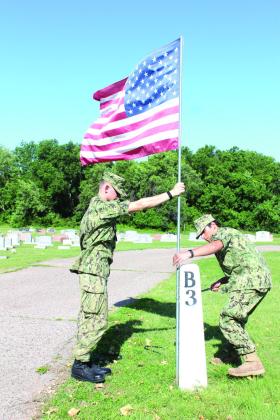 U.S. Naval Sea Cadet Petty Officer Joeby Komppa, left, and Seaman Apprentice Ammar Hammody, with the Patriot Division, secure a flag to a marker at Tecumseh Cemetery. Natasha Dunagan, Countywide &amp; Sun