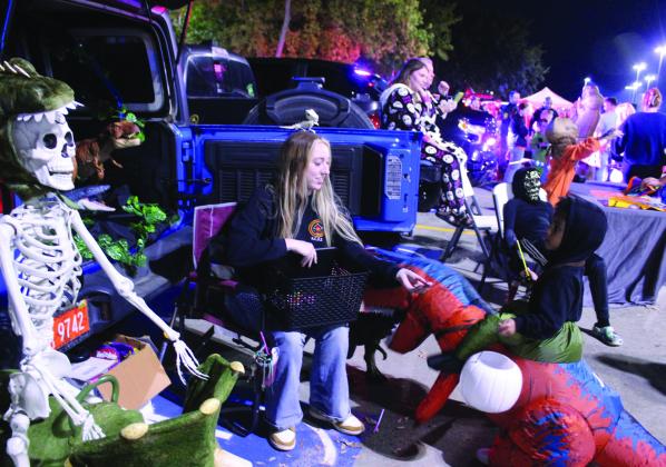 Cortney Farrow, ICW Case Manager with Fire Lodge Children and Family Services, hands candy to T.J. Hawkins, 3, of Shawnee, during the Second Annual First Responders Trunk or Treat, held in the FireLake Arena parking lot on the evening of Oct. 25. Fire Lodge won "Cutest Trunk." Tecumseh Police Department won "Funniest"; Brown and Sons Wrecker took "Scariest"; and, Mabel Bassett received "Most Creative." Natasha Dunagan, Countywide &amp; Sun