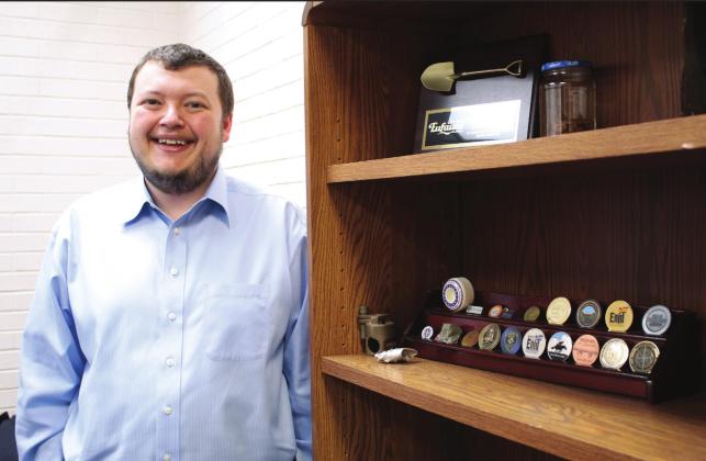 Shawnee Assistant City Manager Jacob Foos stands in his office by a shelf of mementos from other cities where he’s worked. Foos moved to Shawnee and started his current job in Sept. 2021. Countywide &amp;amp; Sun/Natasha Dunagan