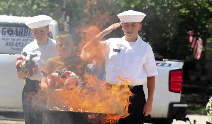 US Naval Sea Cadet Corp. Able Cadet Barrett Boone salutes after ceremonially placing a wornout flag in the flames during the Tecumseh American Legion Post 260 Flag Retirement Ceremony on June 13. Sea Cadets and League Cadets from the Training Ship Oklahoma helped to ceremonially burn 400 flags, donated over two years, as last year's ceremony was rained out. Natasha Dunagan, Countywide &amp;amp; Sun