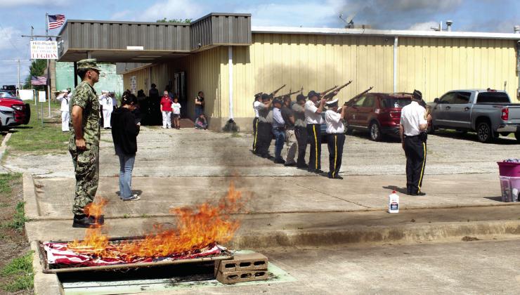 US Naval Sea Cadets Corp. Fire Petty Officer Spencer Tedrow, far left, stands at attention after lighting the first few of 400 US flags, as the Tecumseh American Legion Post 260 Honor Guard gives the gun salute.