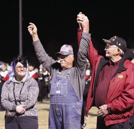 Two Army veterans raise their hands when their service theme song is played and join arms to support each other. At least 30 veterans participated in the "veteran's parade" where they were announced by Tecumseh High School Assistant Band Director Bailey Vaughn and stood on the THS football field. This was part of the Veteran's Day Light Show. Shown are THS student Rebekah Gribble, her father, Fred Sheets - Army/Special Forces, and Larry Tabor - Army.
