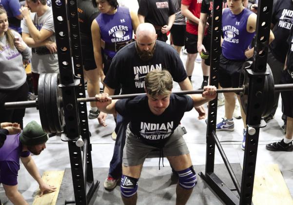 Asher Head Powerlifting Coach Bobby Carnes spots for senior Brogan Culwell as he does squat lifts during a recent powerlifting meet. Culwell is the first person at Asher to join the “1,000-Pound Club.” Photo provided.