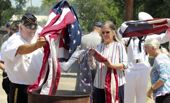 American Legion Post #260 Commander Tom Snodgrass places a flag in a burn barrel for retirement by fire, as Auxiliary Member Julia Watters waits, during the Flag Day Celebration and Flag Retirement in Tecumseh, June 15. Hundreds of flags were donated by the community to be retired at the annual event.