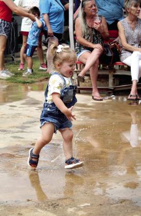 Hazel Reid, 19 months, of McLoud, runs through puddles in front of the stage during The McKedys performance at the McLoud Blackberry Festival.