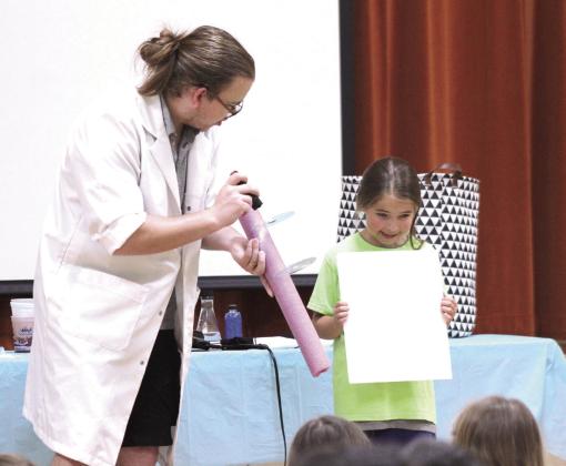 Dr. Arthropod makes rainbows by shining a light through two compact discs onto a white board, with the help of a CPN After-School Program student. Natasha Dunagan, Countywide &amp; Sun
