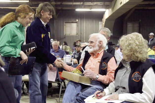 Dr. Joe Taron (center, seated) and Sue Nelson (right) are presented bid confirmations by 4-H and FFA representatives. File photo