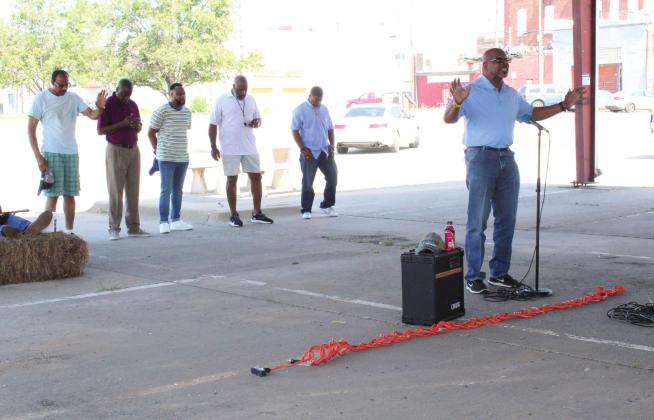 Pastor C.I. Prevost leads a prayer for the media and educators during the Juneteenth Prayer Service, held at the pavilion on Bell and 7th streets, in Shawnee,  June 18. Five other pastors from the area, standing behind him, also led prayers for community leaders and other topics. They are, from left, Joe Wilkes, David Henry, Vincent Roland, Darryl K. Fields, and Anthony P. Rhone.