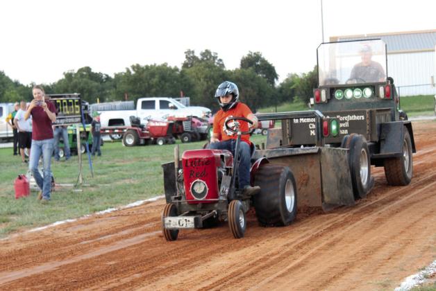 Jon Caldwell, the great-grandson of announcer Dale Caldwell, drives one of his great-grandfather's tractors, 'Little Red,' and pulls 166.56 feet during the Garden Tractor Pulls at the Pottawatomie County Free Fair on Sept. 6.
